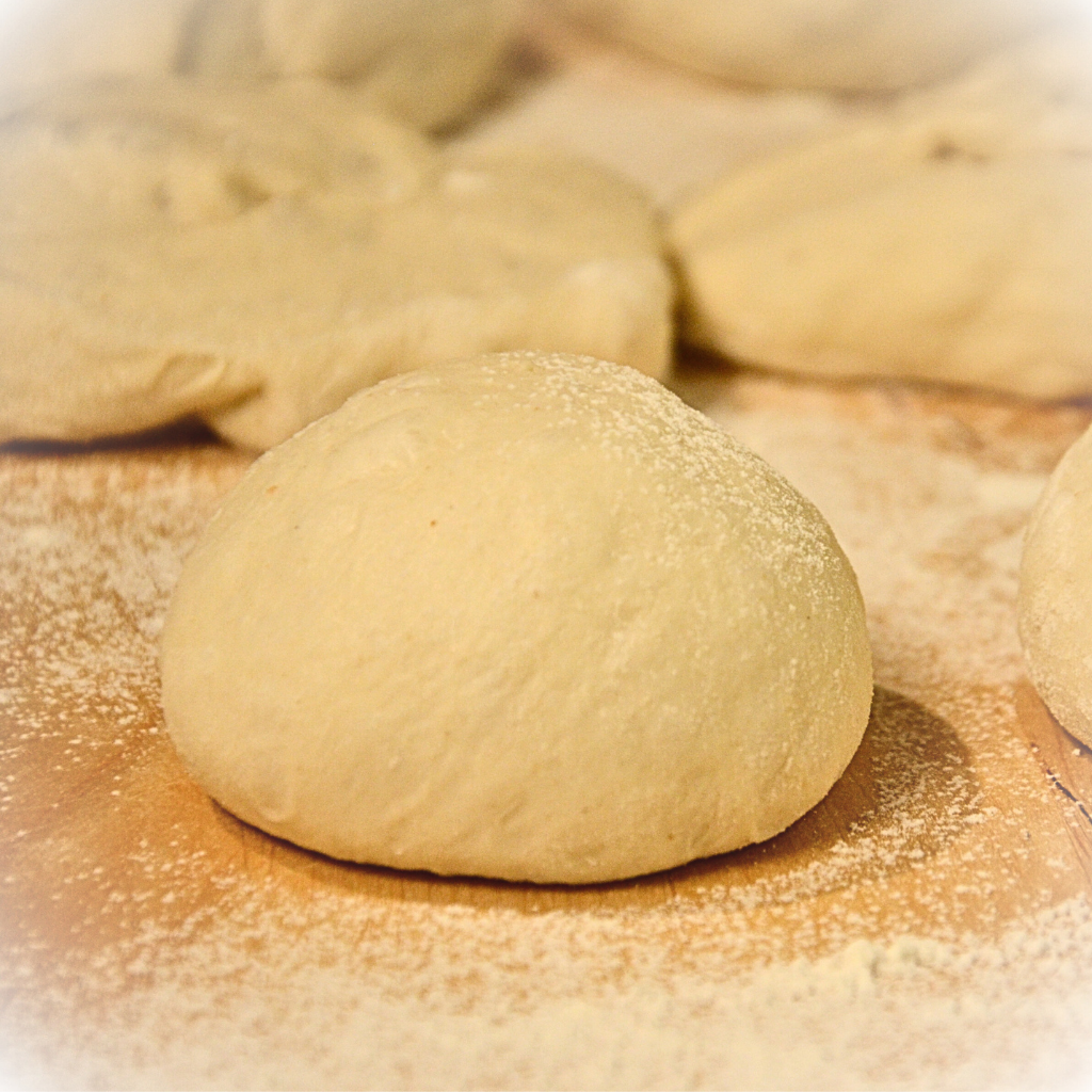 Geschliffener Brötchenteigling auf einer bemehlten Holzarbeitsplatte